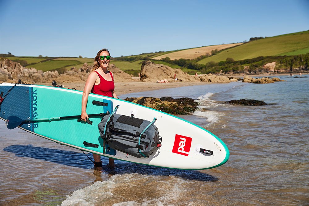 Woman carrying Red Original SUP on beach