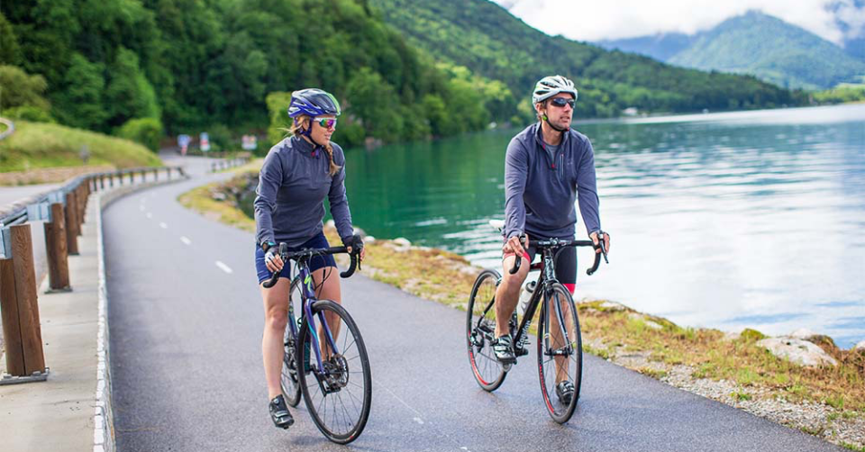 Man and woman cycling next to lake