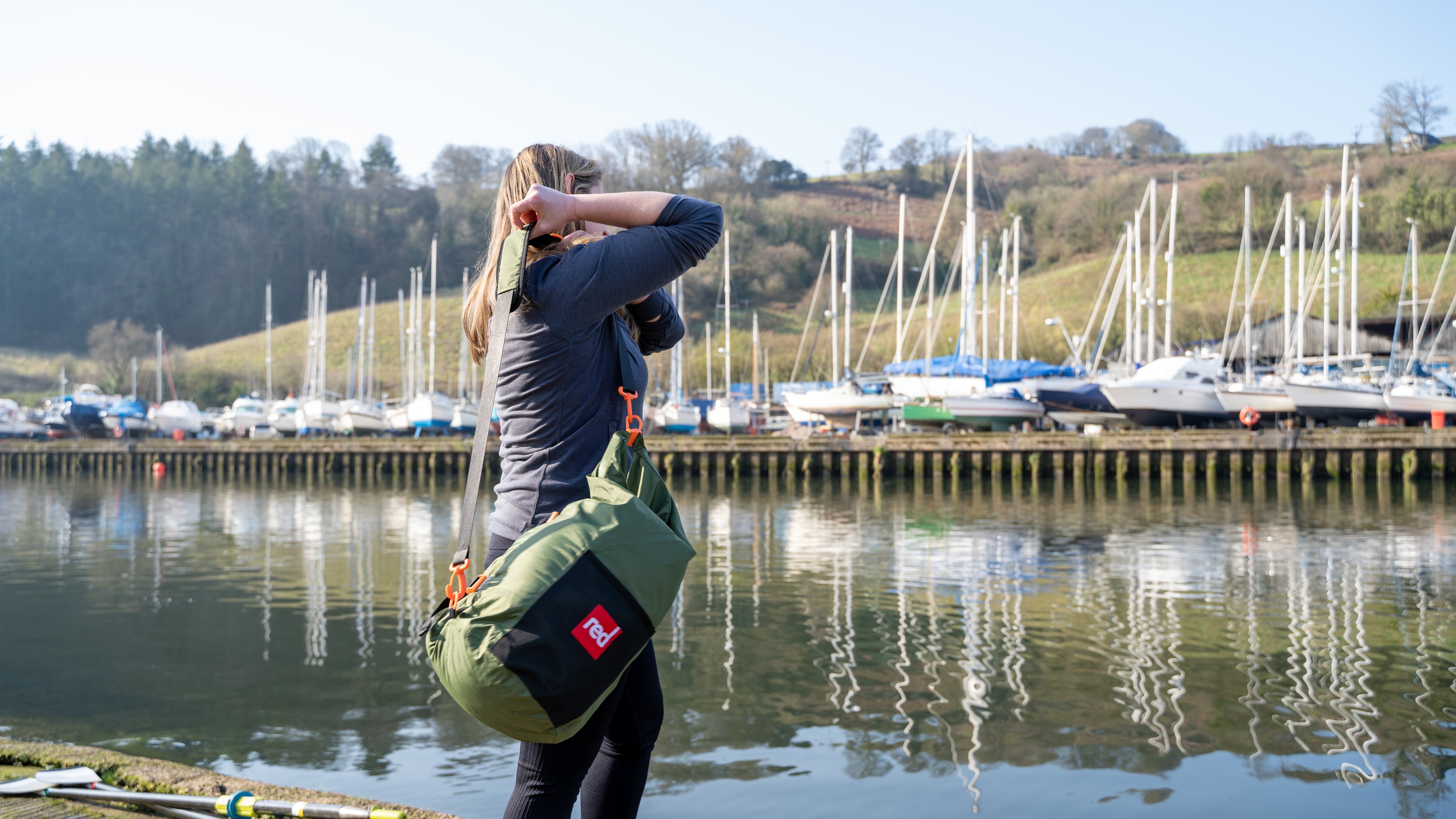 woman using a red original stash bag in green