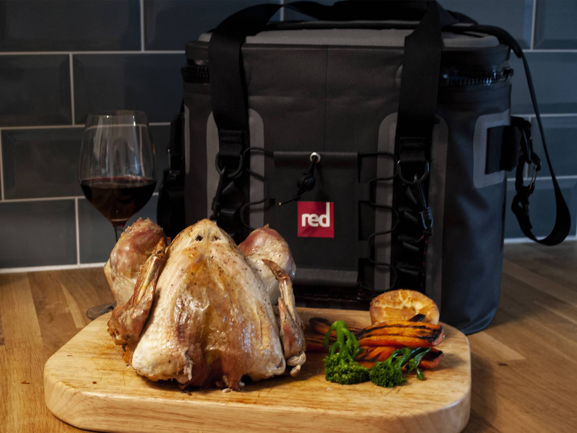 The Red Original Cooler Bag Bhind A Cooked Christmas Turkey With Vegetables And A Glass Of Wine