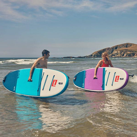 A man and a woman in the sea with Red Paddle Co inflatable paddle boards from the 2022 range