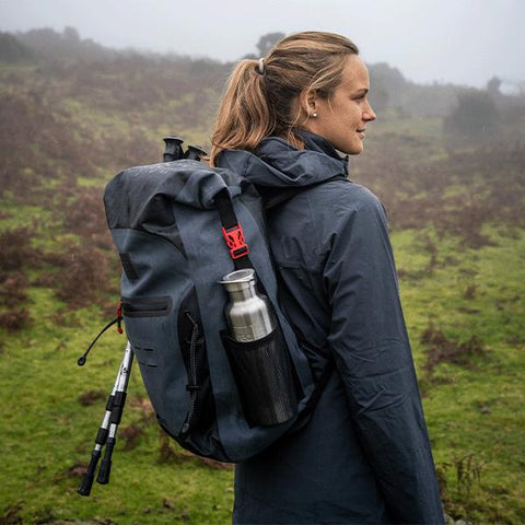 Woman wearing Red Original Active Jacket, Waterproof Backpack with Stainless Steel Drinks Bottle whilst walking in a field on the moors in the mist