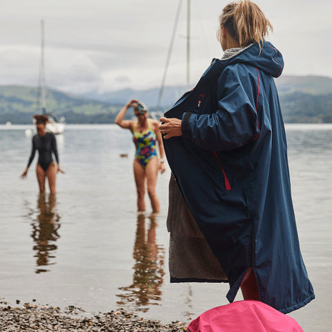 A group of women changing on the shore of a lake after going for a swim featuring the Red Original Pro Change Robe EVO