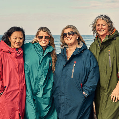 A group of smiling women stood on the beach after going for a swim wearing the Red Original Pro Change EVO