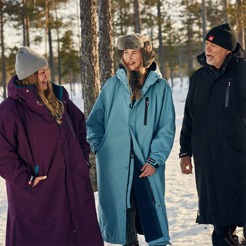 2 women and a man amongst snow and fir trees wearing Red Original Pro Change Robe EVO in Sea Mist, Mulberry Wine and Stealth Black