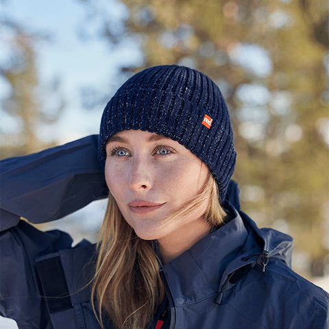 Woman in the trees and the snow wearing Red Original Merino Beanie in Navy and Active Jacket in Grey