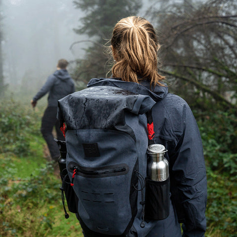 Man and woman hiking in the woods wearing Red Original Waterproof Active Jacket, Waterproof Backpack and Insulated Stainless Steel Water Bottle