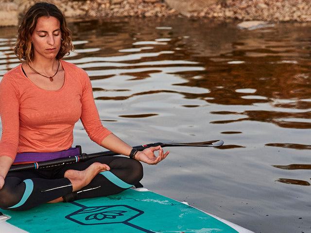 Woman Practicing Yoga On A Paddleboard