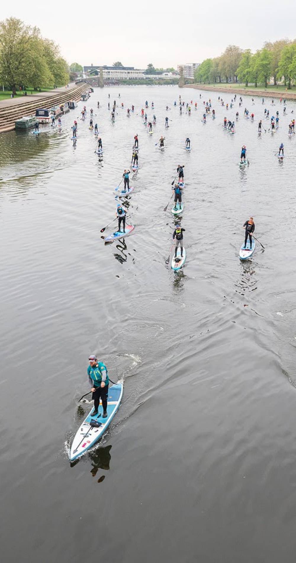 A group of paddle boarders on a river featuring the Red Paddle Co 14' Elite inflatable Race Board