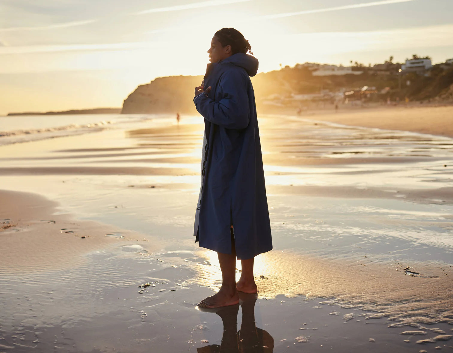 A woman stood on the beach during sunrise wearing the alter evo robe