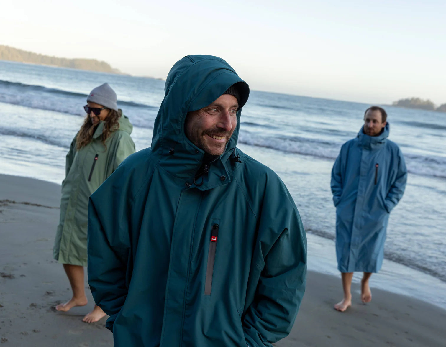 A group of people walking on the beach wearing the alter evo robes